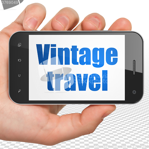 Image of Tourism concept: Hand Holding Smartphone with Vintage Travel on display