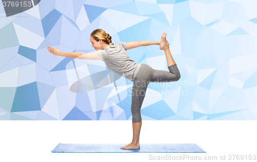 Image of woman making yoga in lord of the dance pose on mat