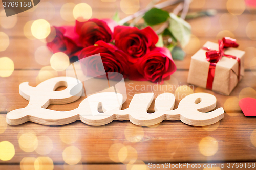 Image of close up of gift, word love, red roses and hearts