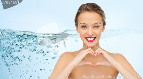 Image of smiling young woman showing heart shape hand sign