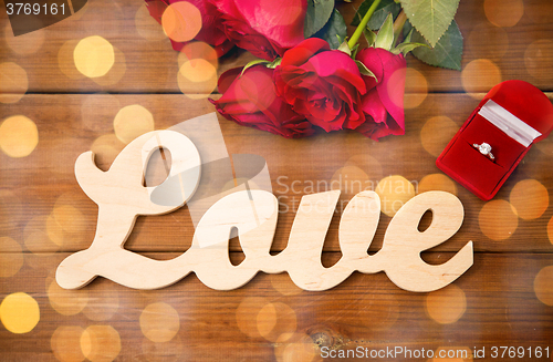 Image of close up of diamond ring, red roses and word love