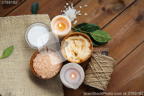 Image of close up of natural body scrub and candles on wood