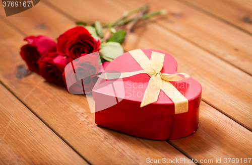 Image of close up of heart shaped gift box and red roses