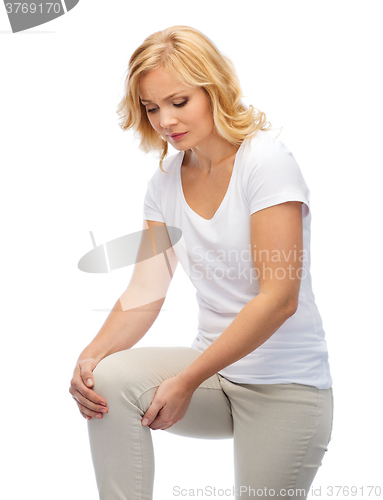 Image of unhappy woman suffering from pain in leg at home