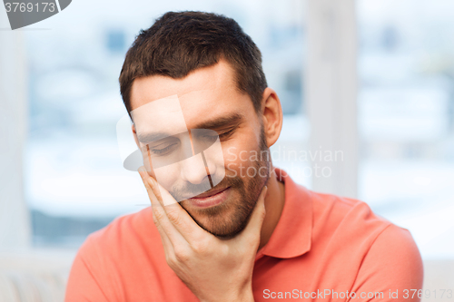 Image of unhappy man suffering toothache at home