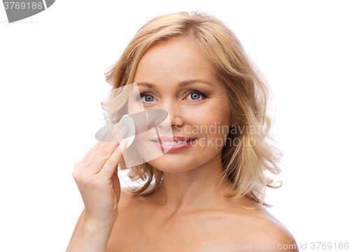 Image of happy woman cleaning face with cotton pad