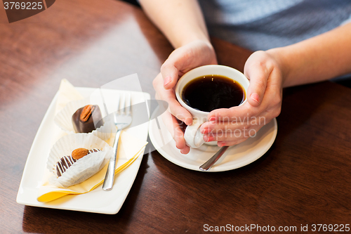 Image of close up of woman holding coffee cup and dessert