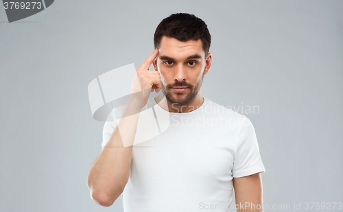 Image of man with finger at temple over gray background