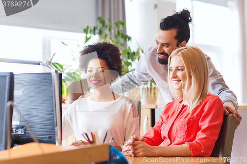 Image of happy creative team with computer in office