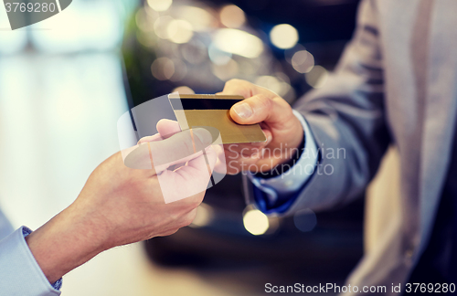 Image of customer giving credit card to car dealer in salon