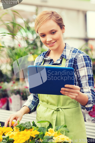 Image of happy woman with tablet pc in greenhouse