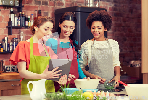 Image of happy women with tablet pc cooking in kitchen