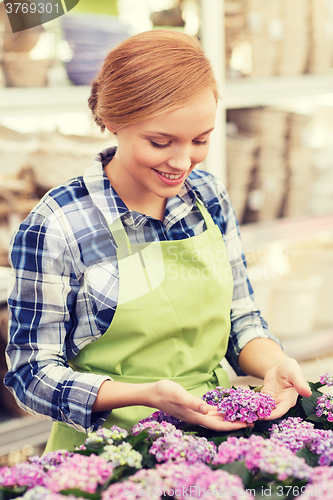 Image of happy woman taking care of flowers in greenhouse