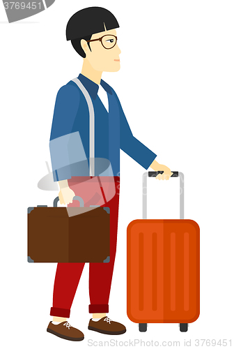 Image of Man with suitcase on wheels and briefcase.