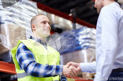 Image of worker and businessmen with clipboard at warehouse