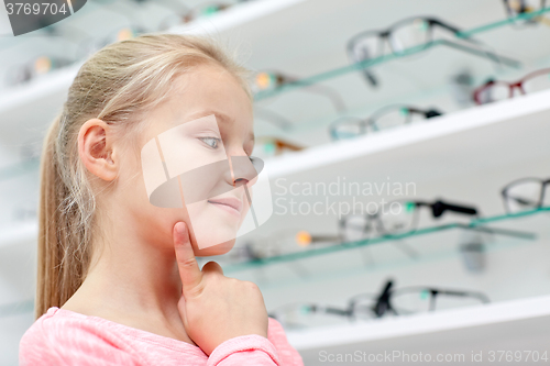 Image of little girl choosing glasses at optics store