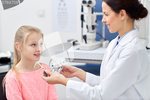 Image of optician with trial frame and girl at clinic