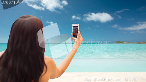 Image of young woman taking selfie with smartphone