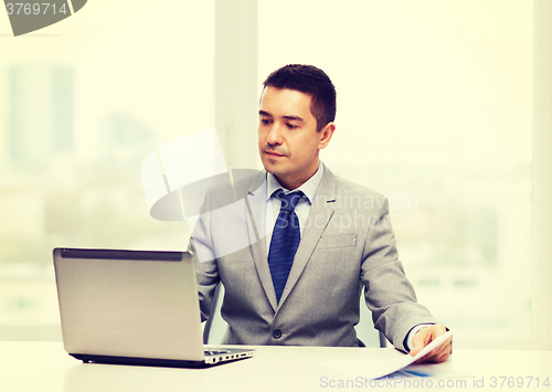 Image of businessman with laptop and papers