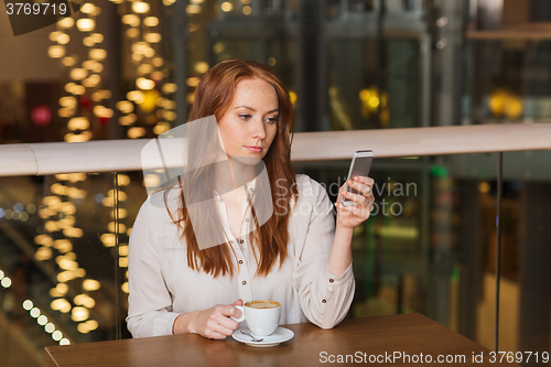 Image of woman with smartphone and coffee at restaurant