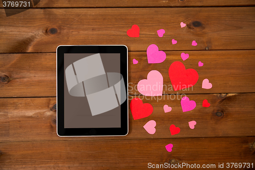 Image of close up of tablet pc and hearts on wood