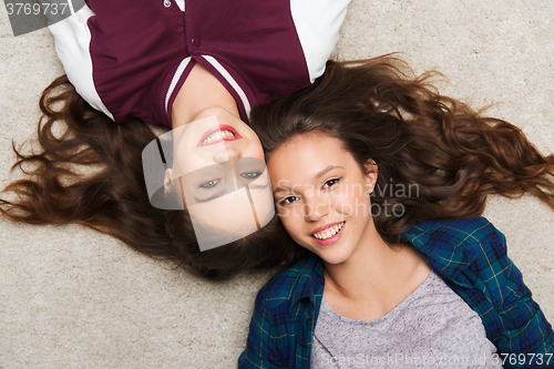 Image of happy smiling pretty teenage girls lying on floor