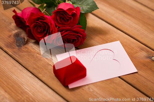 Image of close up of gift box, red roses and greeting card
