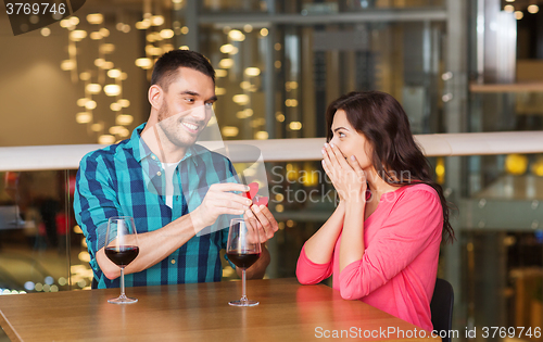 Image of man giving engagement ring to woman at restaurant