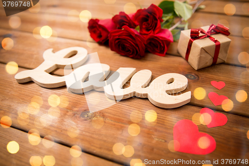 Image of close up of gift, word love, red roses and hearts