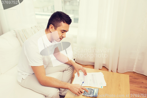 Image of man with papers and calculator at home