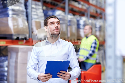 Image of businessman with clipboard at warehouse