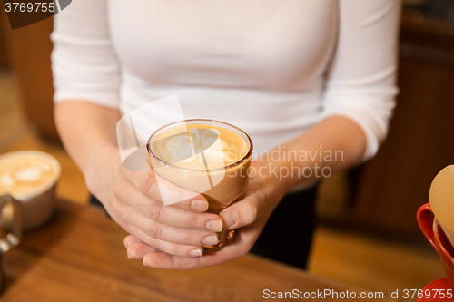 Image of close up of hands with latte art in coffee cup