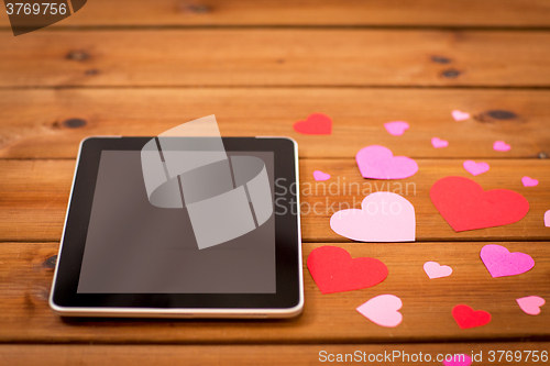 Image of close up of tablet pc and hearts on wood