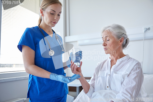 Image of nurse giving medicine to senior woman at hospital