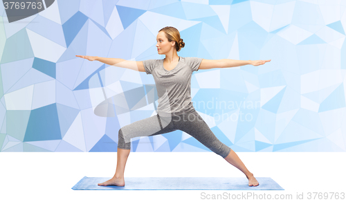 Image of woman making yoga warrior pose on mat