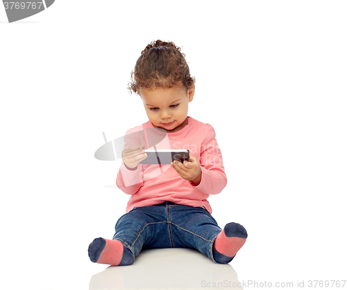 Image of smiling little baby girl playing with smartphone