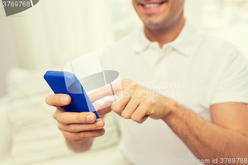 Image of close up of happy man with smartphone at home