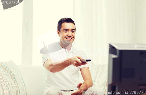 Image of smiling man with remote control watching tv