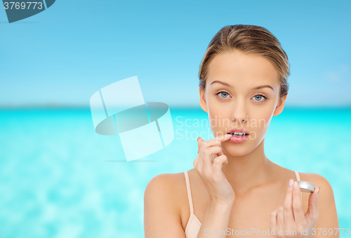 Image of young woman applying lip balm to her lips