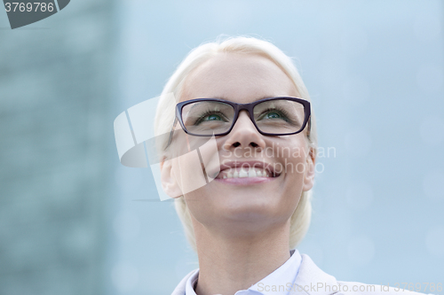 Image of young smiling businesswoman over office building