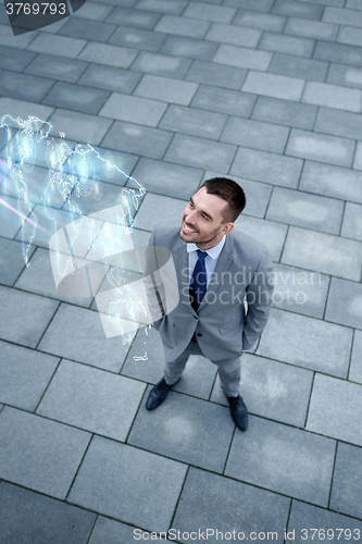 Image of businessman with world map hologram outdoors