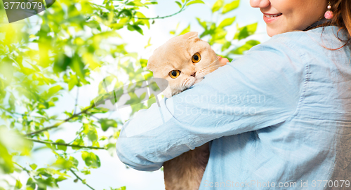 Image of woman holding scottish fold cat over tree