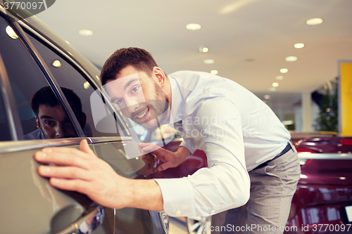 Image of happy man touching car in auto show or salon