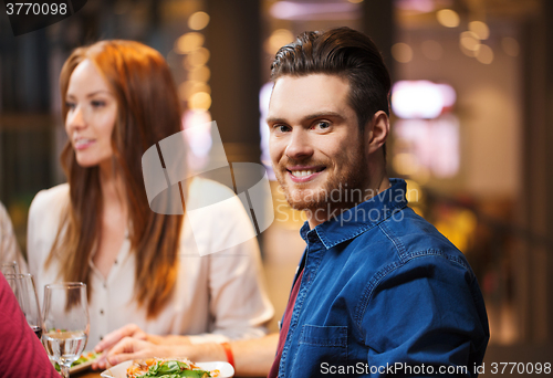 Image of happy man with friends having dinner at restaurant