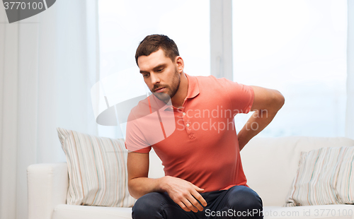 Image of unhappy man suffering from backache at home