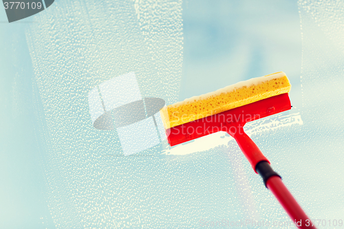 Image of close up of hand cleaning window with sponge