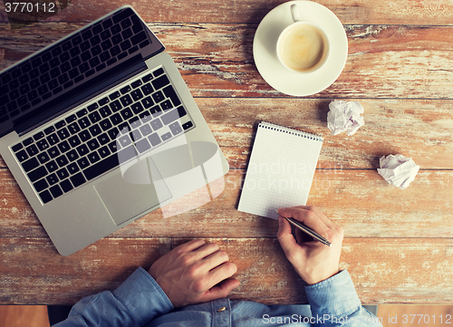 Image of close up of male hands with laptop and notebook