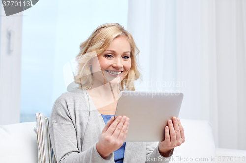 Image of happy middle aged woman with tablet pc at home