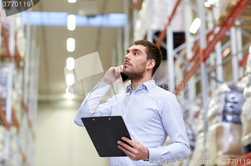 Image of man with clipboard and smartphone at warehouse