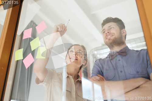 Image of happy creative team writing on blank office glass